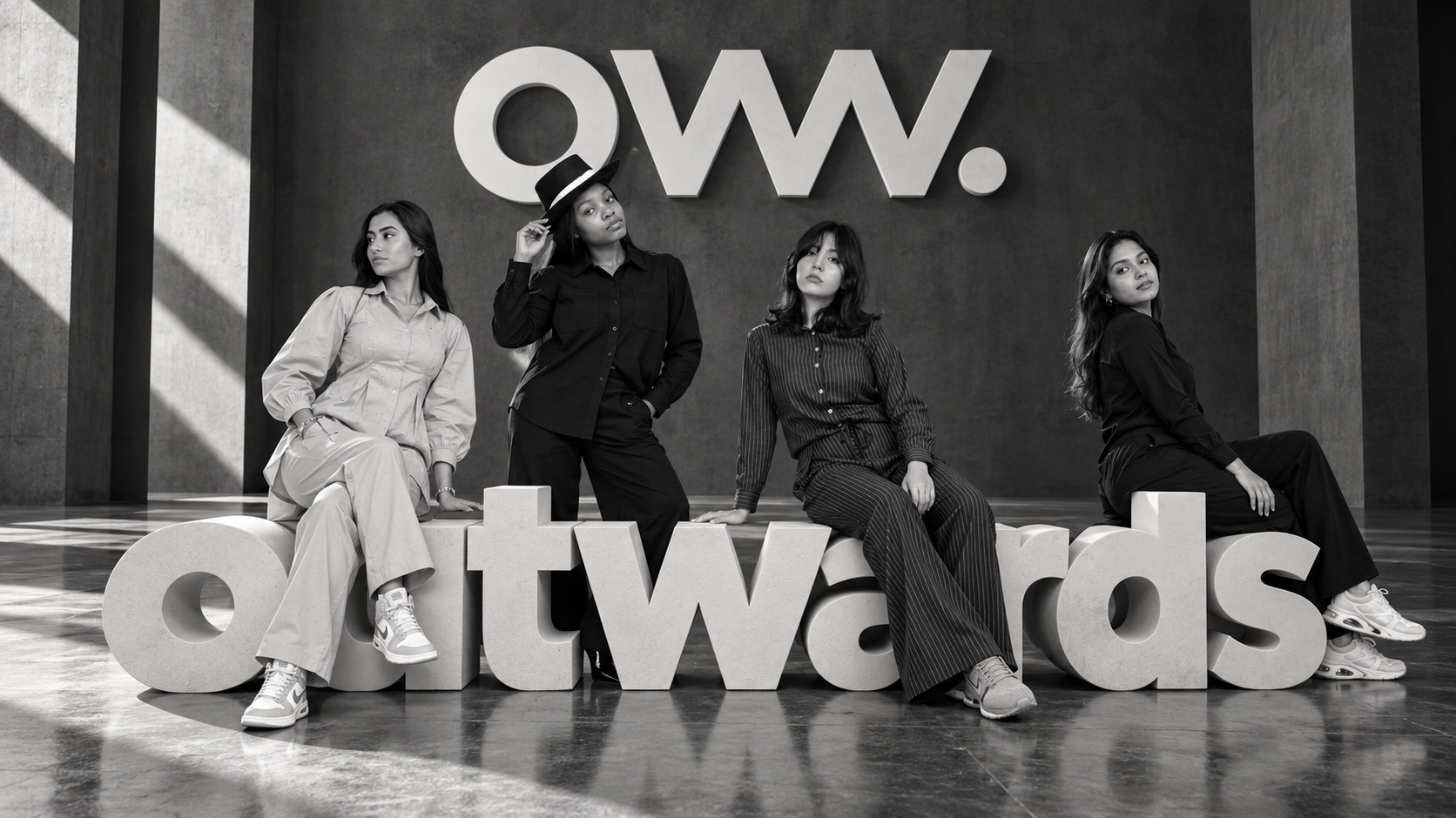 Four OUTWARDS looks posed before a large OUTWARDS sign